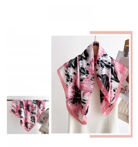 Detailed view of pink floral satin scarf featuring abstract blossoms and stitched edges