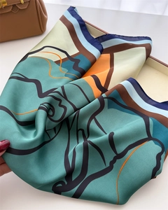 Detailed view of abstract geometric silk scarf with hand-rolled edges on a leather bag