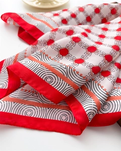 Close-up of silk scarf showing geometric patterns, red H-buckle print and hemmed edges