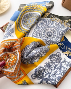 Detail of baroque silk scarf featuring lemon yellow scroll patterns and glossy texture
