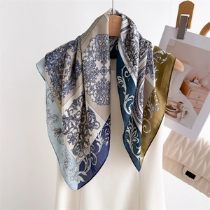 Elegant retro floral silk square scarf with baroque patterns hanging on a wooden hanger