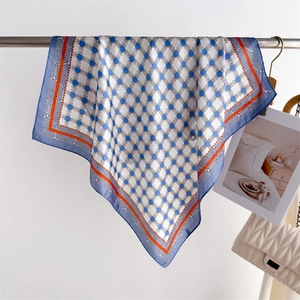 Detailed close-up of geometric silk scarf with blue chain patterns and orange borders