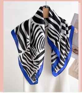 Detail of zebra pattern silk scarf with bright blue borders hanging on a wooden hanger