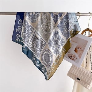 Elegant vintage silk square scarf with baroque print hung next to a quilted handbag
