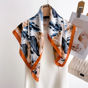 Close-up of artistic floral silk scarf featuring deep blue and caramel abstract patterns