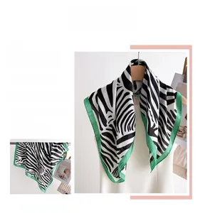 Macro detail of zebra print silk scarf with striking green border trim and glossy texture