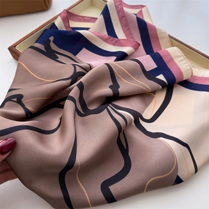 Detail of silk scarf with geometric floral pattern displayed on a wooden tray