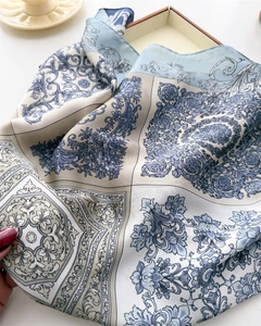 Detailed close-up of a silk scarf featuring baroque floral patterns in light blue and white