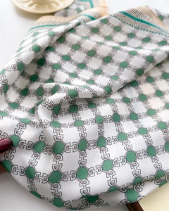 Detailed texture of green and white silk scarf featuring geometric H chain patterns