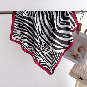Detail of silk zebra print square scarf featuring elegant red border and smooth texture