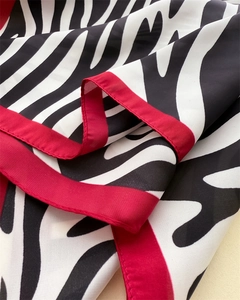 Detail of soft silk square scarf showing zebra print pattern and red hemmed edges