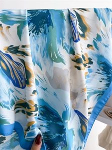 Detail shot of the silky floral scarf with blue and green abstract patterns