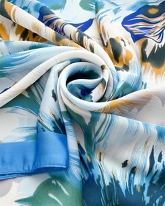 Close-up of silk scarf with vibrant blue and yellow floral prints and fine hem edges