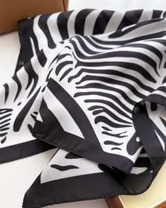 Close-up of zebra print silk scarf with fine texture against a brown leather bag