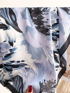 Detailed view of the smooth silk texture and artistic floral patterns of this elegant scarf