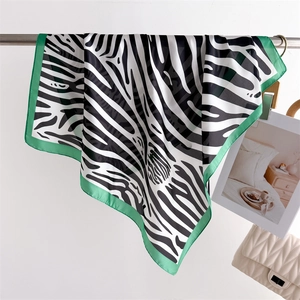 Detail of zebra print silk scarf with vibrant green borders displayed on a wall