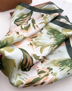 Detailed close-up of glossy floral silk scarf with abstract green and apricot ink pattern