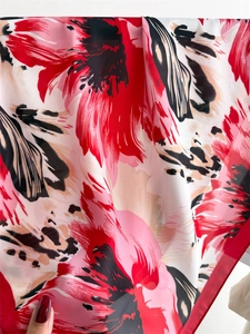 Detail of floral print silk scarf showing soft folds and vibrant red flower pattern