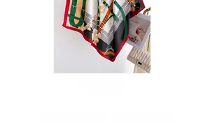 Détail d'un foulard en soie à imprimé équestre, bord rouge et sac à main beige