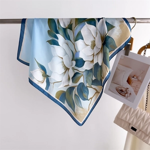 Close-up of light blue silk scarf with magnolia print hanging on a metal rod