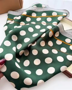 Close-up of green satin scarf featuring white polka dots and bright orange stripe details