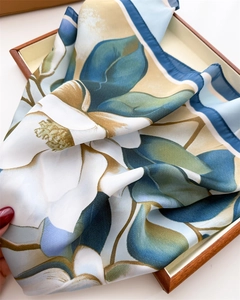 Detail of silk scarf showing white floral ink print with elegant deep blue stitched edges