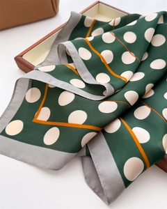 Detailed view of silk square scarf featuring bold white polka dots and orange linear accents