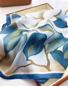 Detailed view of elegant white magnolia print on silk scarf with premium hemmed edges