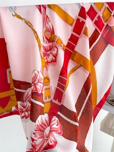 Détail d'un foulard en soie rose avec imprimés équestres et boucle métallique brillante