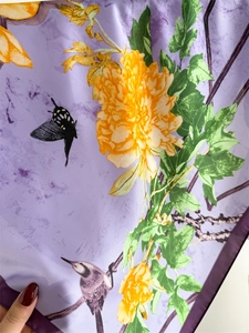 Detailed close-up of purple ink-wash silk scarf featuring floral and bird patterns