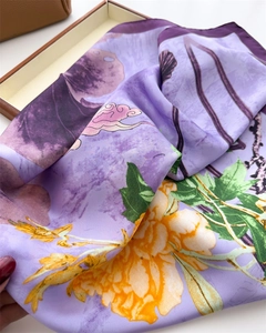 Detail of silk scarf showing ink lotus print, satin texture, and purple birds design