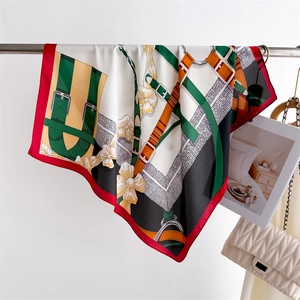 Détail du foulard en soie avec imprimé équestre et motifs floraux en rouge éclatant