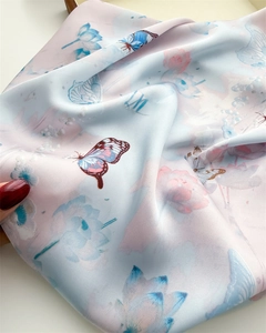Close-up of silk scarf showing elegant floral butterfly print and soft gradient texture