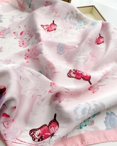 Close-up of elegant pink silk scarf featuring intricate butterfly and floral prints