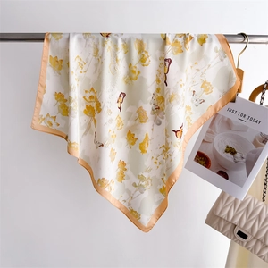 Detail of silk scarf with yellow floral and butterfly prints hanging on a metal rod