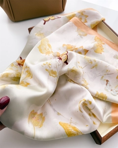 Close-up of silk square scarf featuring yellow lotus and butterfly print with elegant drape