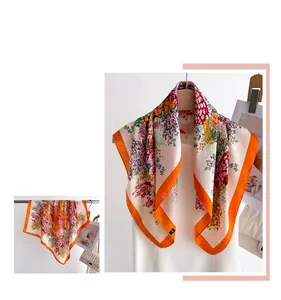 Detailed close-up of premium floral print silk scarf with a vibrant orange border finish