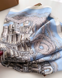 Macro view showing the architectural print and silky texture of the square scarf