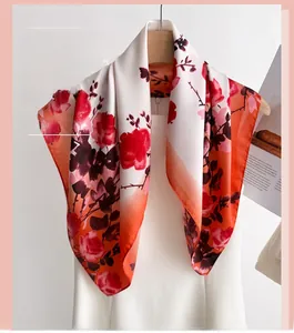 Détail d'un foulard en soie à fleurs rouges et dégradé orange sur un cintre élégant