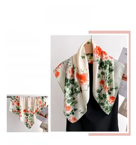 Détail du motif floral orange et de la texture satinée soyeuse d'un foulard en soie