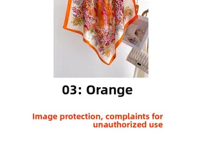 Detail of floral silk-feel scarf with orange border beside a stylish handbag