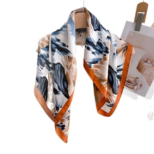 Abstract floral silk scarf with dark blue pattern and orange borders on wooden hanger