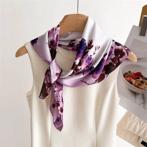 Détail d'un foulard en soie violet à fleurs noué sur une robe blanche en satin brillant
