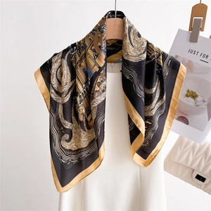 Artistic architectural print silk scarf in navy and gold draped on a wooden hanger