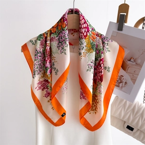 Elegant floral print silk square scarf with bright orange border on a mannequin display
