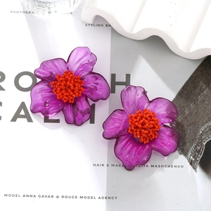Bohemian purple resin flower earrings with orange handmade bead center on a white background