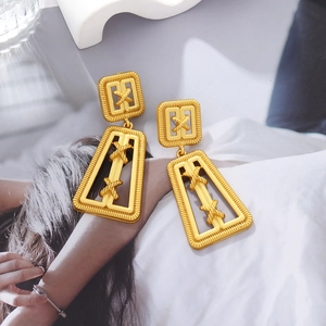 Retro gold geometric trapezoid earrings with ribbed texture and X motif in high fashion shot