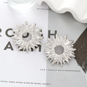 Macro shot of silver sunburst earrings with hollow circular design on a fashion magazine