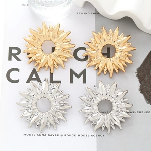 Macro view of gold and silver sunflower earrings with unique textured metal finish