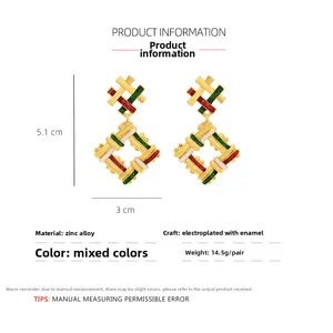 Detail view of woven texture earrings with red green and white enamel on gold frame